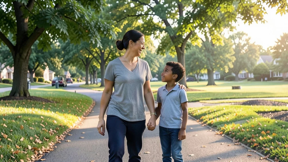 A divorced parent and one school-age child walk side by side through a quiet neighborhood park, sharing a calm and honest conversation
